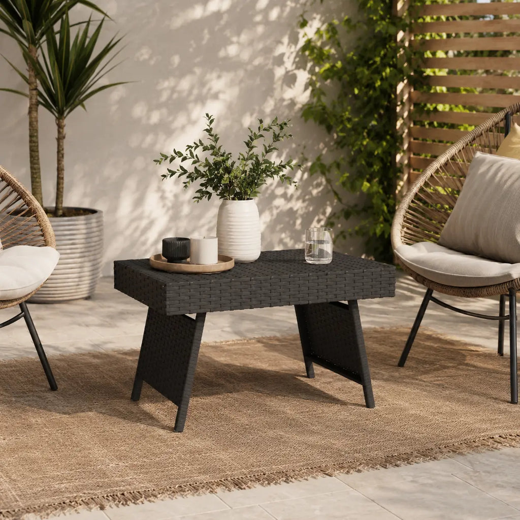 Table basse extérieure en résine tressée noire sur terrasse moderne avec ambiance jardin élégante