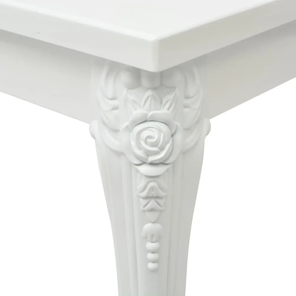 Gros plan sur le pied sculpté de la table basse blanche, avec motif floral décoratif et finition laquée brillante