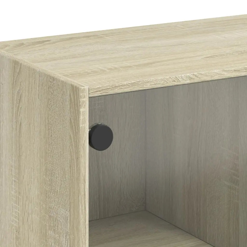Gros plan sur une table basse en bois clair montrant la finition effet chêne et le système de panneau en verre coulissant