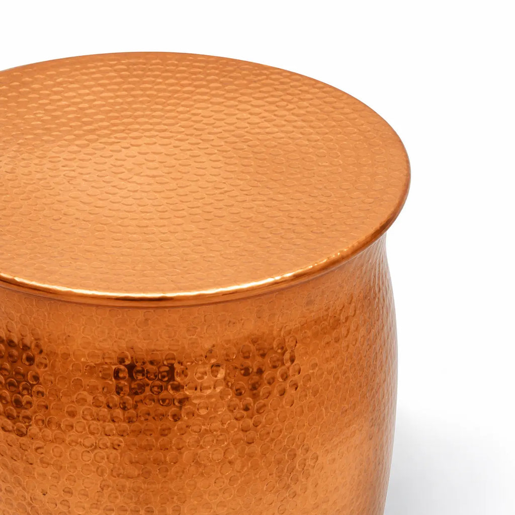 Gros plan sur table basse cuivrée martelée, finition métallique texturée brillante au design contemporain