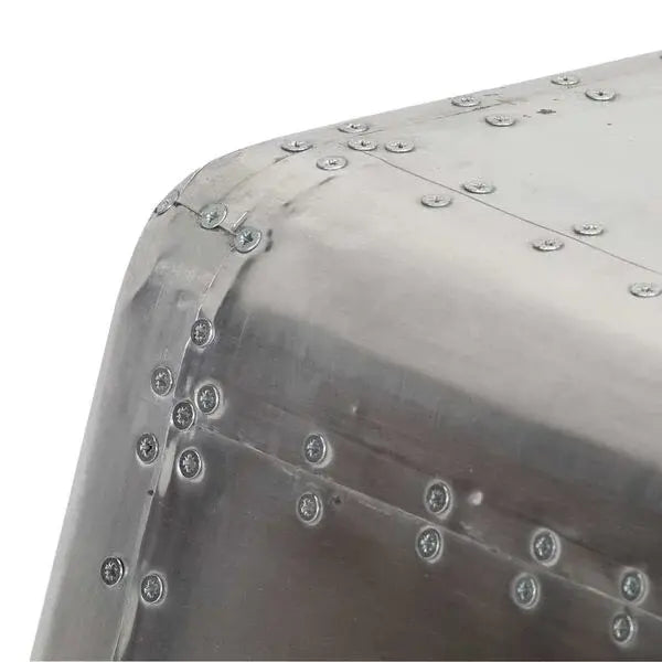 Gros plan sur finition métal argenté rivetée avec angles arrondis, détail table basse industrielle style aviation